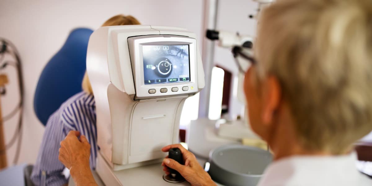 woman sitting with ophthalmic technician for optical coherence testing to screen vision for glaucoma.