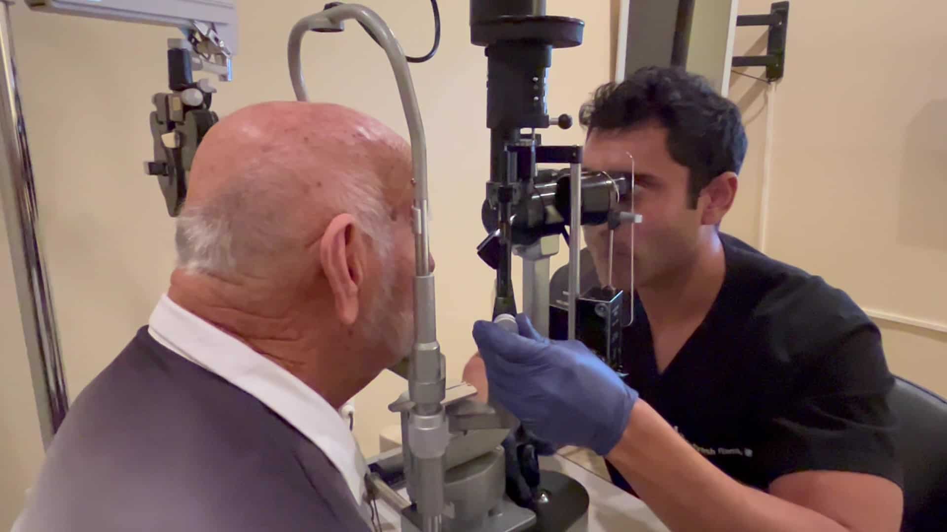 Man sitting at slit lamp with eye doctor examining eyes