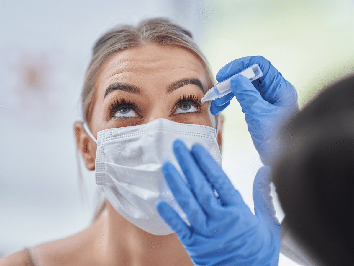 Woman with mask getting dilation drops at eye exam