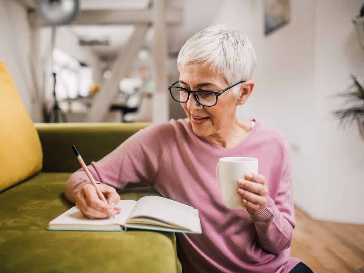 older attractive woman writing in journal planning upcoming eye exam