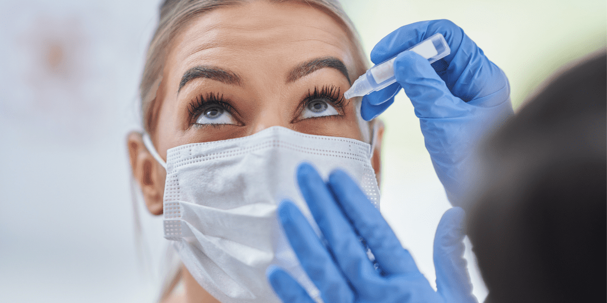 Woman with mask getting dilation drops at eye exam