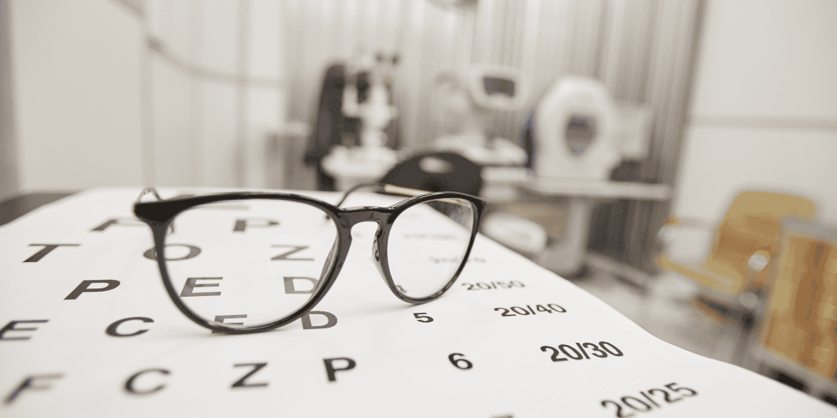 Close-up image of glasses placed on an eye chart, symbolizing the importance of eye exams and vision health.