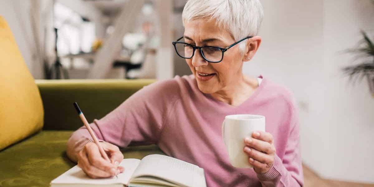 older attractive woman writing in journal planning upcoming eye exam