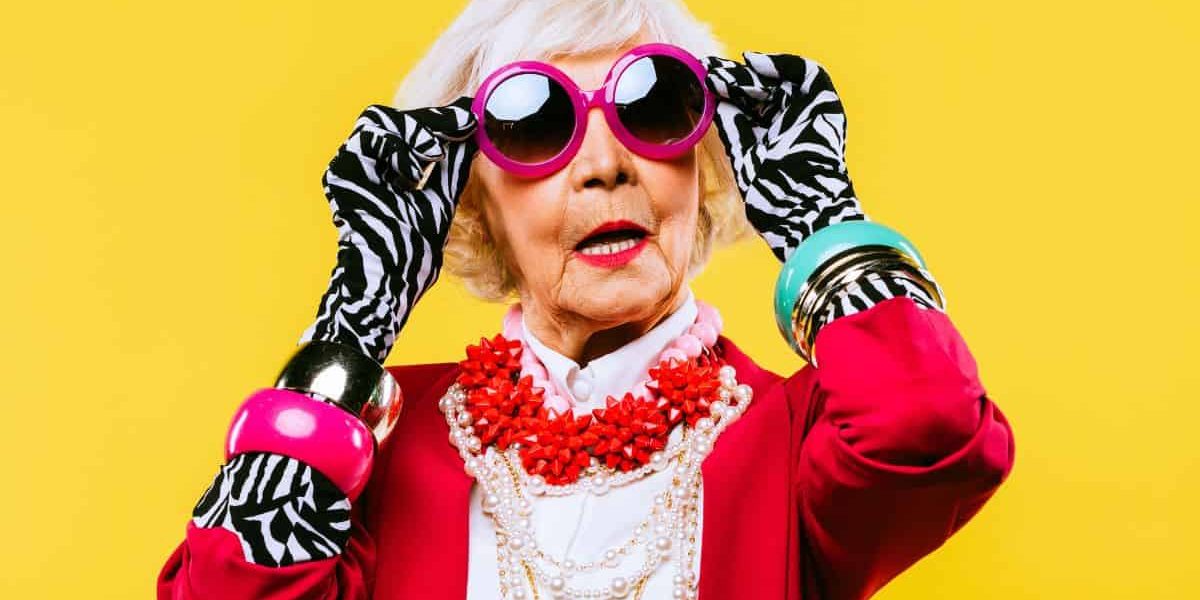 Stylish grandma wearing festive sweater and putting on sunglasses.