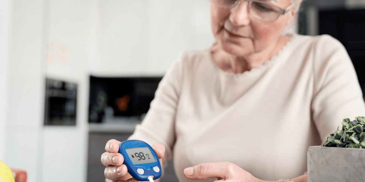 Woman sitting at table wearing eyeglasses testing blood sugar