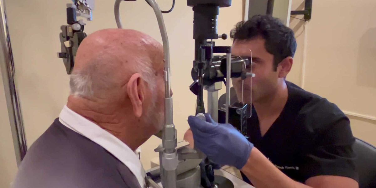 Man sitting at slit lamp with eye doctor examining eyes